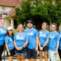 Alumni pose in front of the Alumni House